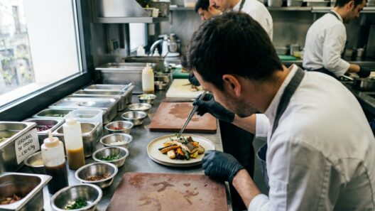 Manos de un cocinero emplatando un plato de temporada en una cocina profesional madrileña durante la preparación del servicio de noche